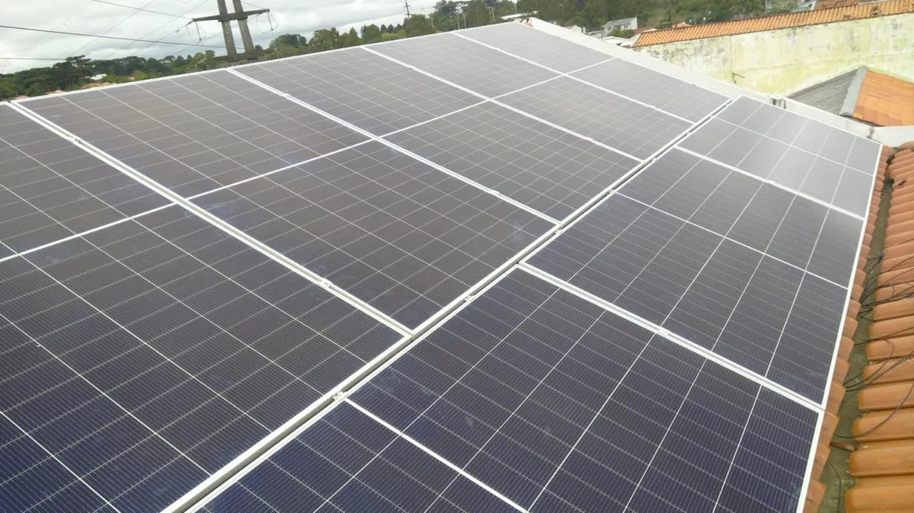 Painéis solares fotovoltaicos instalados em telhado residencial, com o bairro ao fundo
